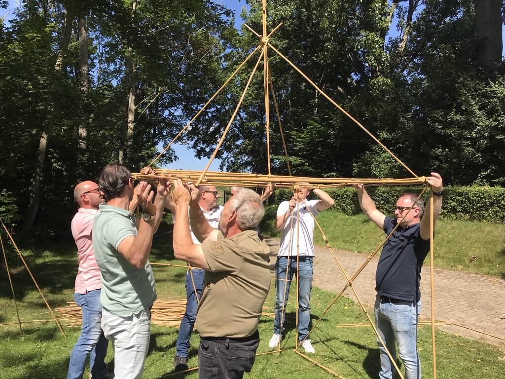 Team tilt een grote bamboester omhoog tijdens de teambuildingactiviteit Bamboestieken